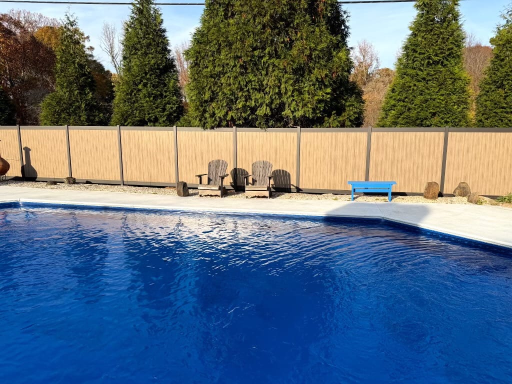 Aluminum vertical privacy fence installed around a backyard pool with clean post lines