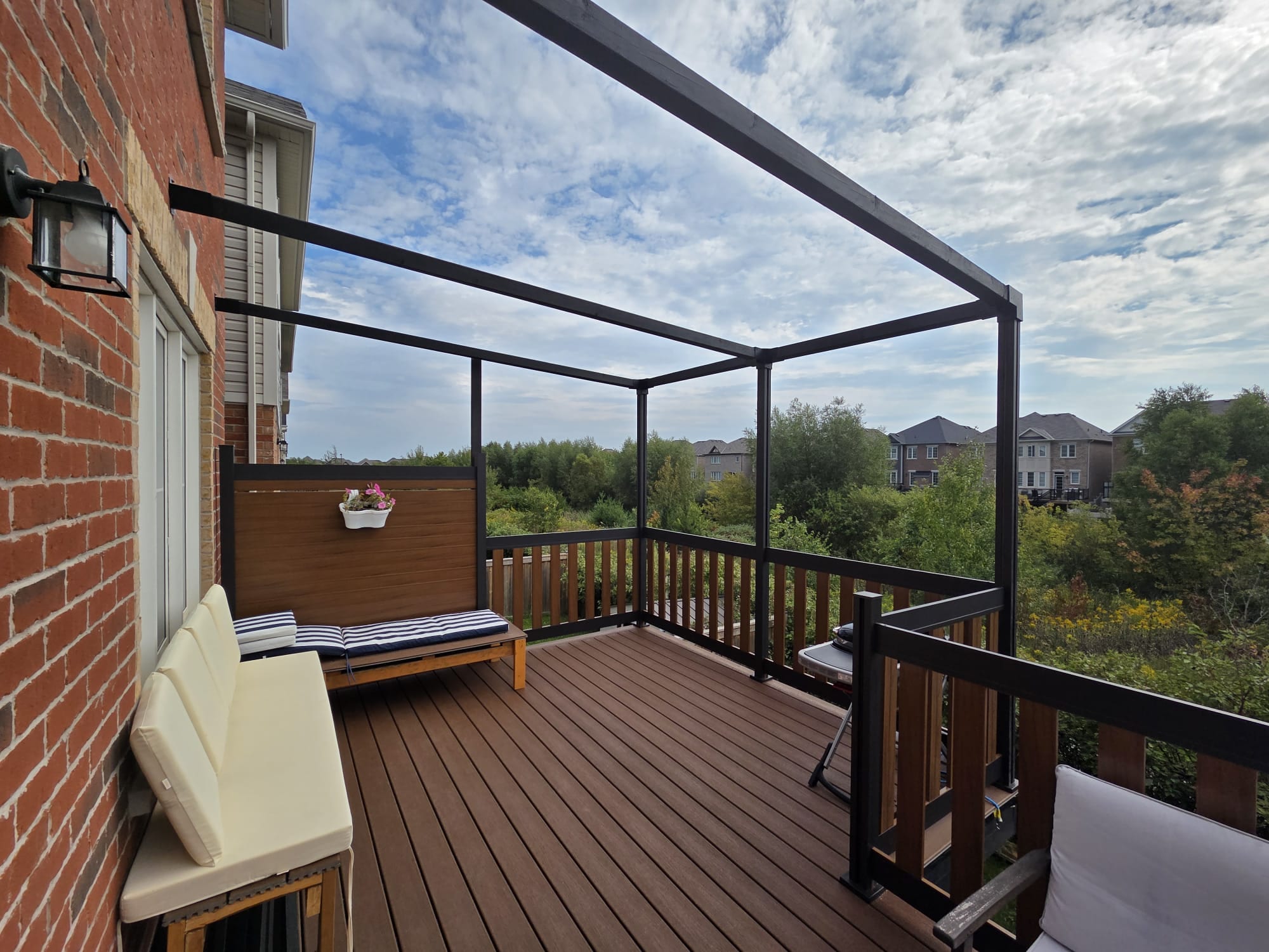 Aluminum fence and matching railing installed along a backyard deck with wood-grain finish
