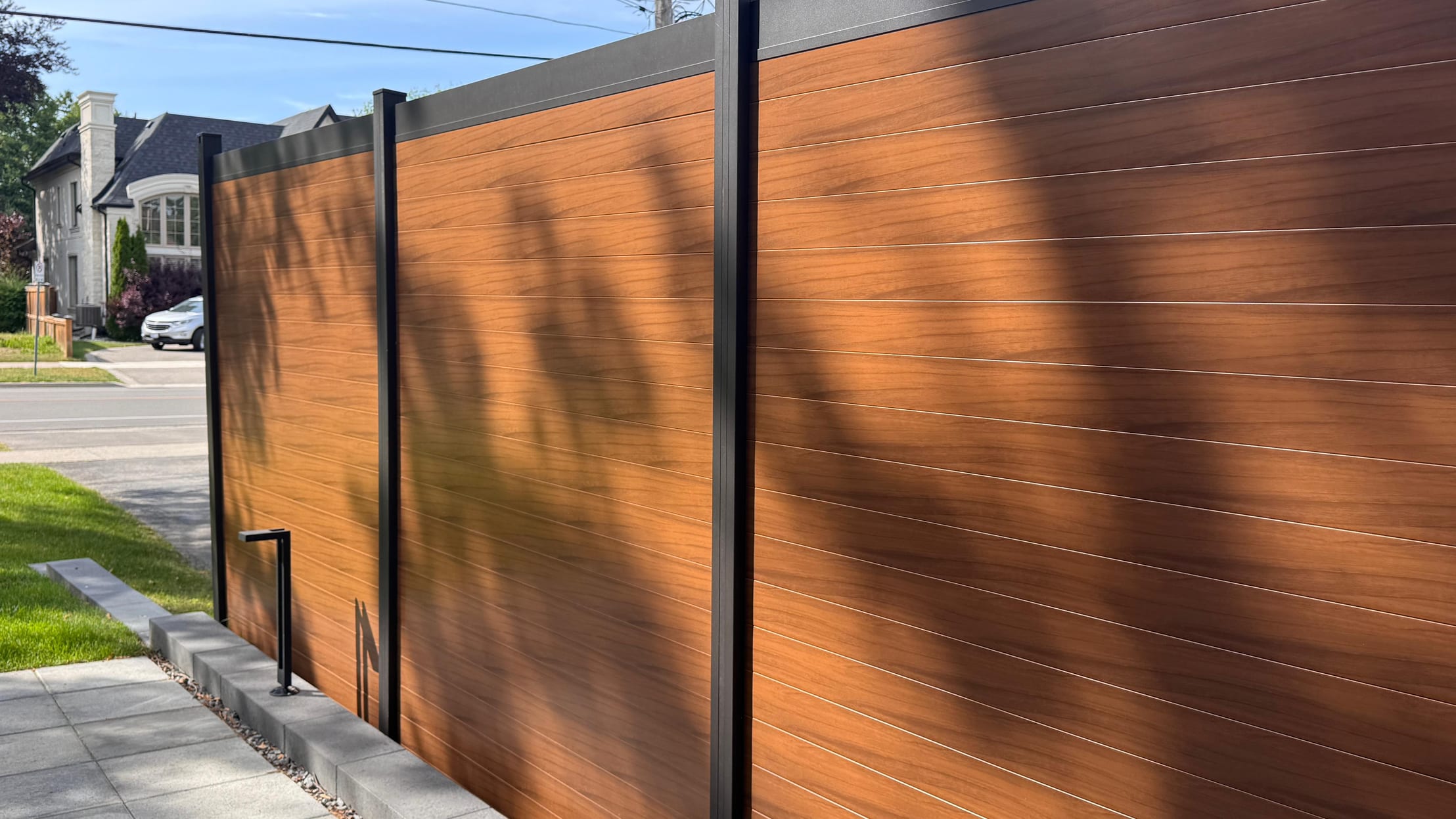 Brown walnut aluminum privacy fence panels installed along a Canadian residential property